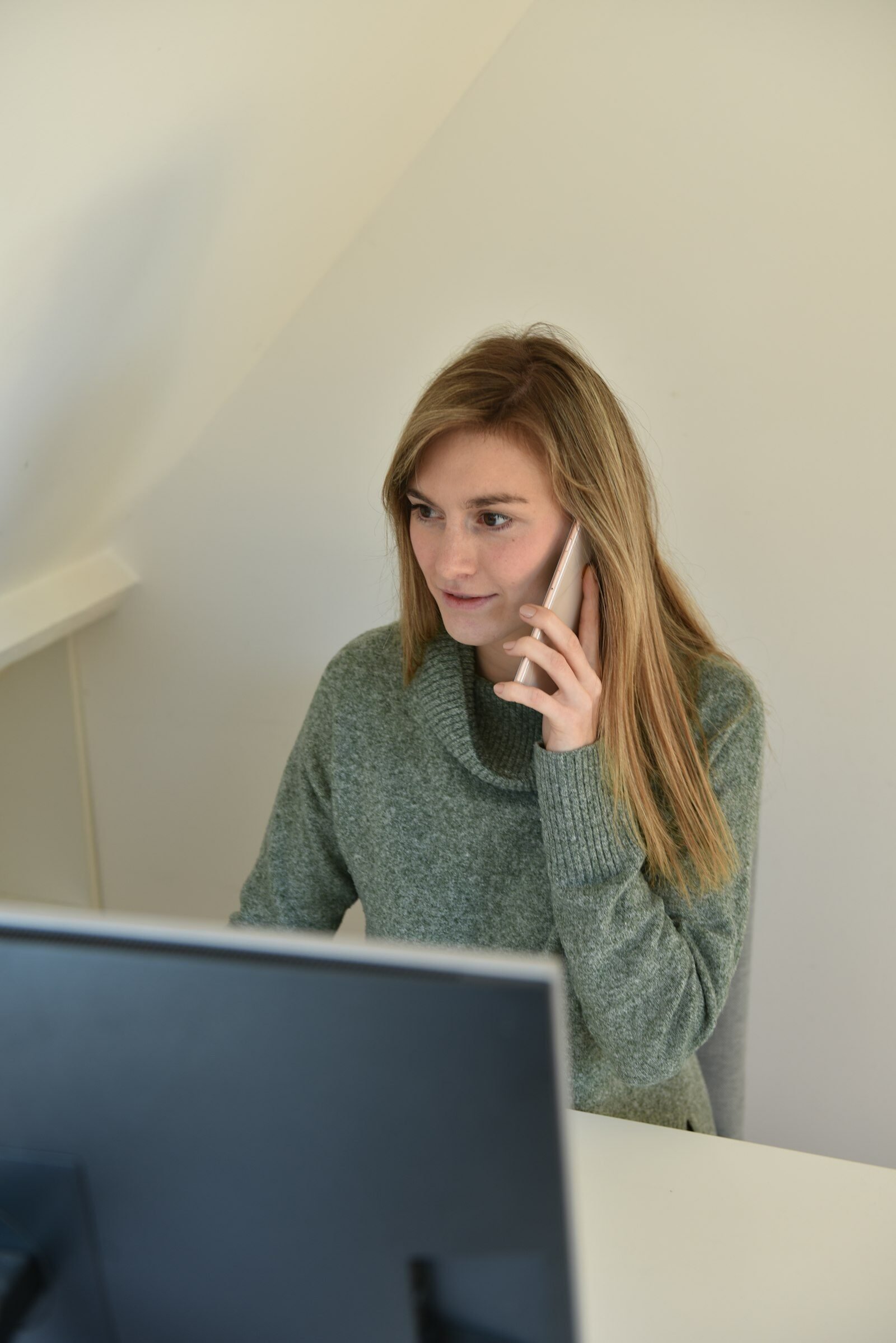 Business owner answering a customer inquiry on her phone at her computer