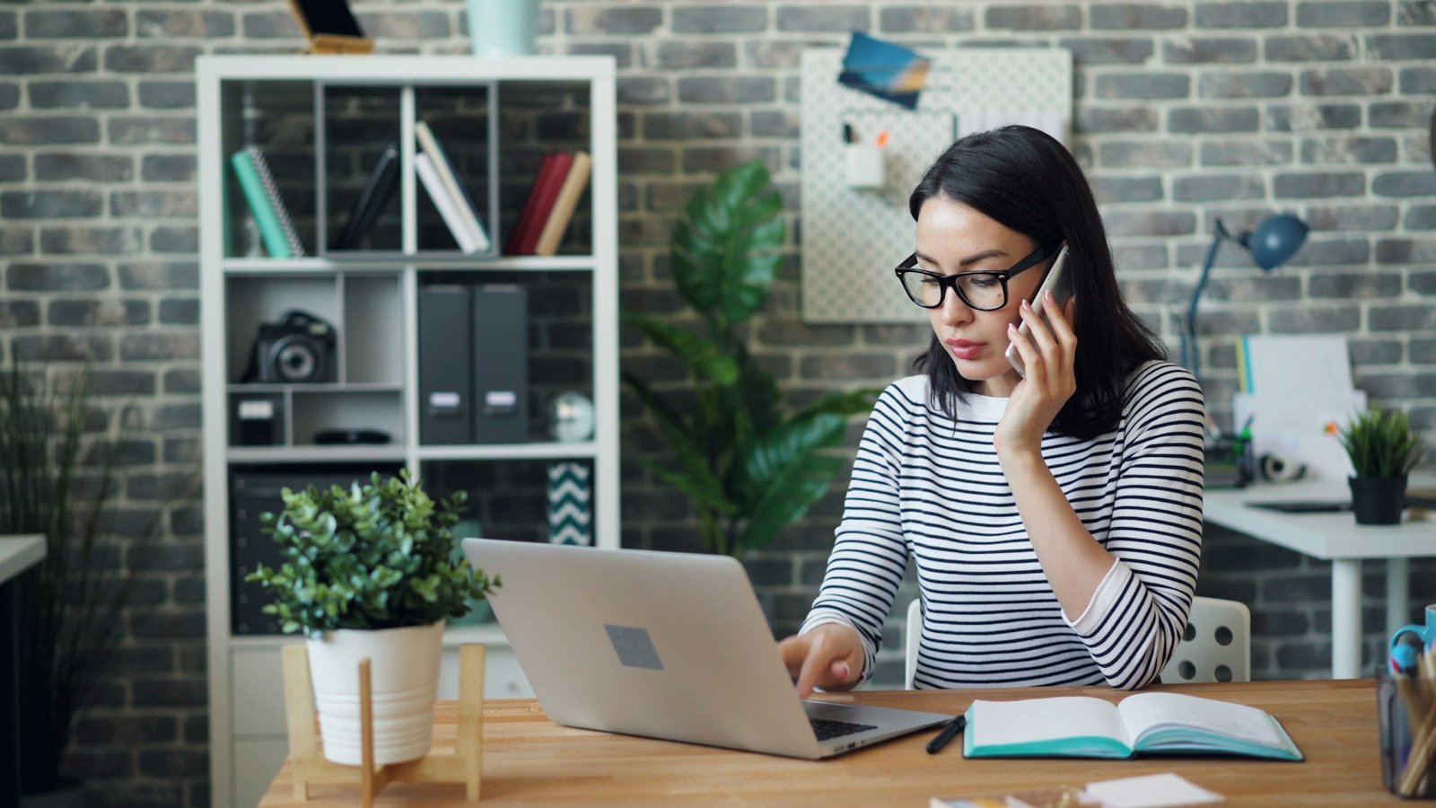 Business owner answering a customer call while working on her laptop