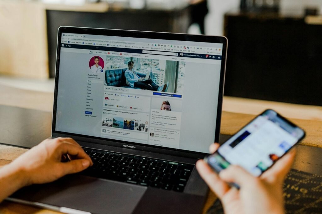 Person using Facebook on a laptop and a smartphone