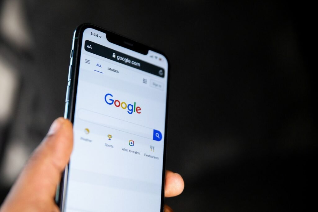 Hand holding a smartphone showing the Google search page