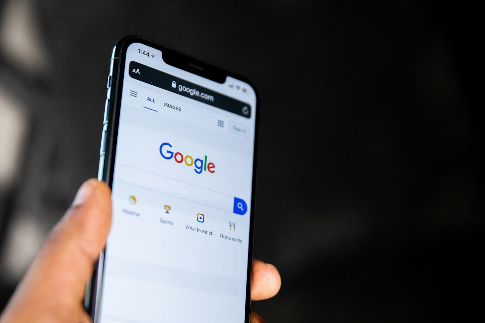 Hand holding a smartphone showing the Google search page