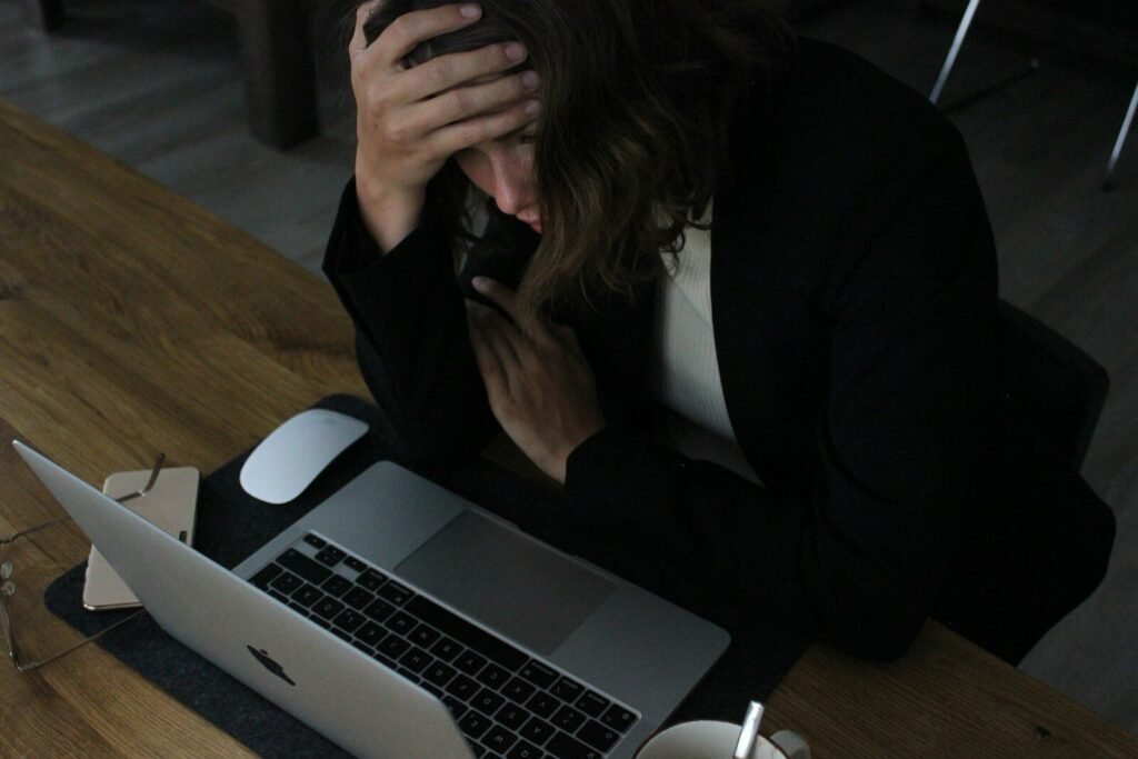 Overwhelmed business owner with head in hands at her laptop
