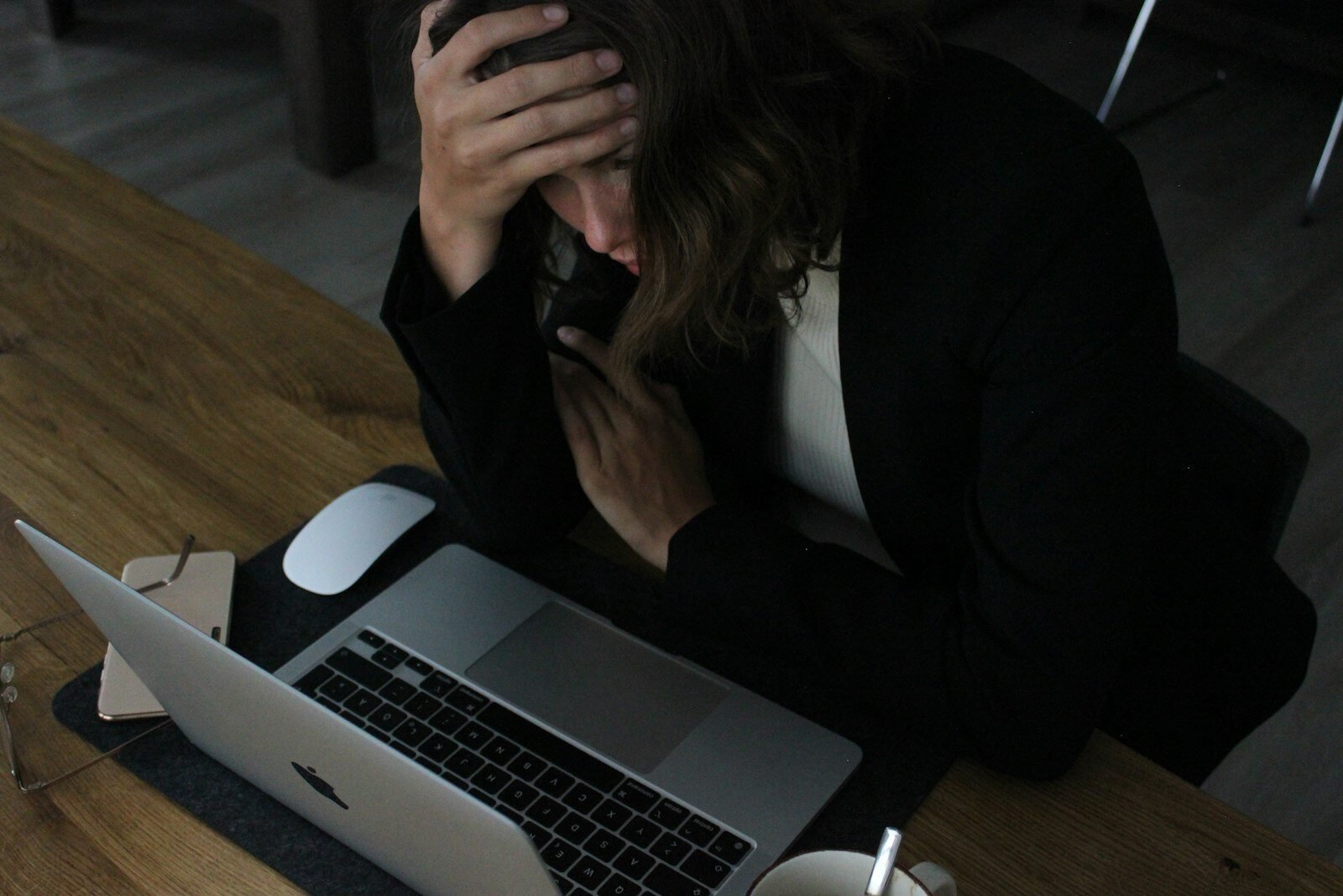 Overwhelmed business owner with head in hands at her laptop
