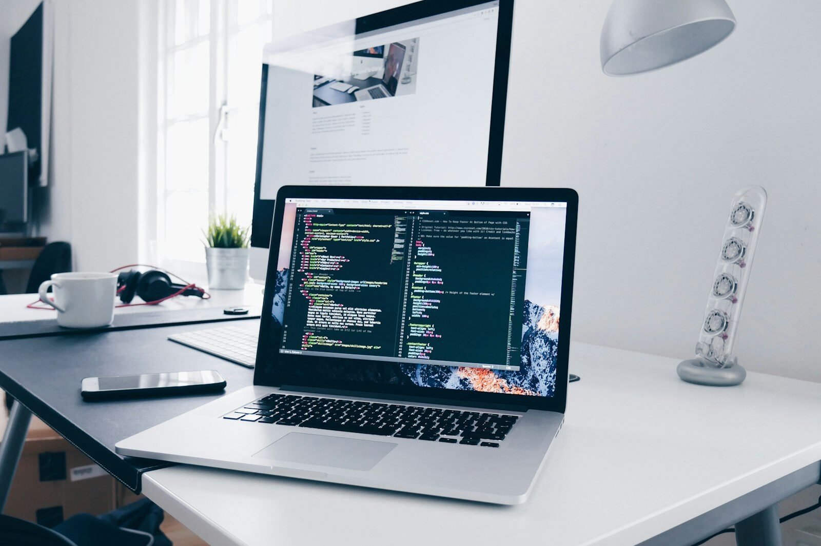 Laptop showing website code on a web developer’s desk
